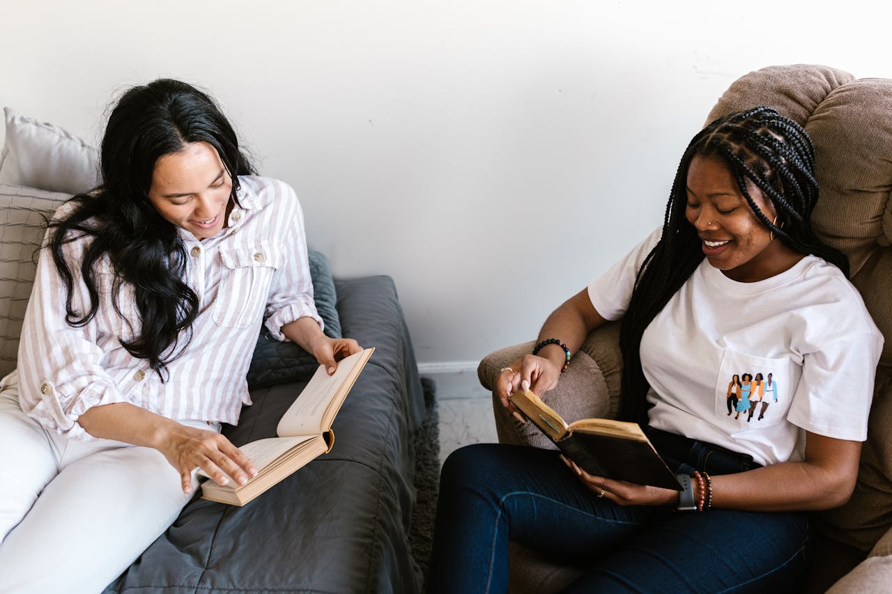 Two young women reading books in a cozy indoor setting, enjoying a study session.